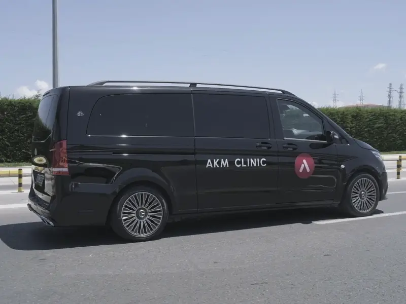 A black luxury Mercedes van branded with the AKM Clinic logo, providing private VIP transfer services for international patients arriving in Istanbul for surgery.