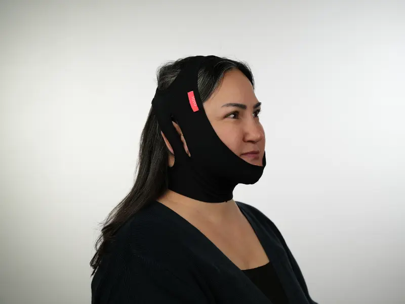 Patient wearing a black post-operative compression garment, which is recommended to be worn for one week after a Deep Plane Facelift in Turkey to minimize swelling and support facial contours.