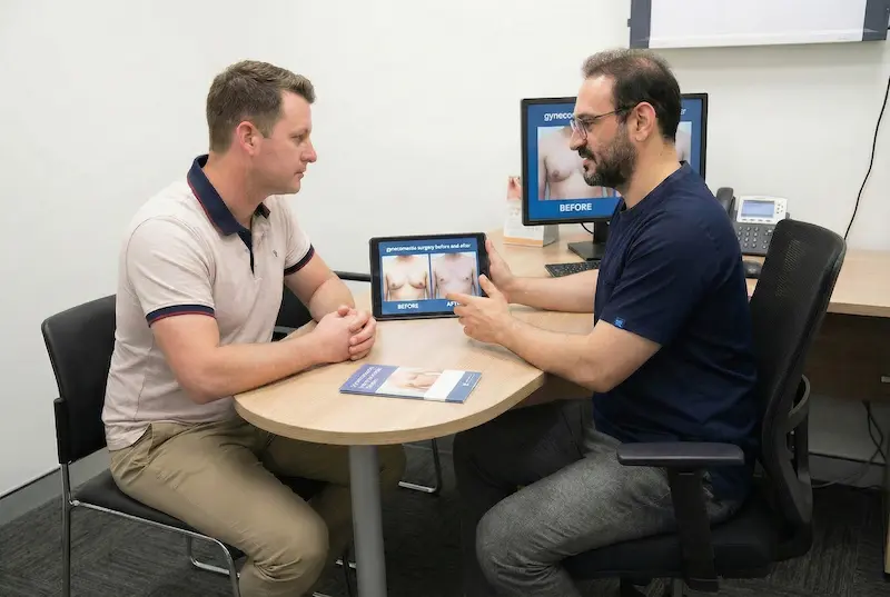 Ideal Candidate for Gynecomastia Surgery consultation showing surgeon explaining male breast reduction results on a screen.