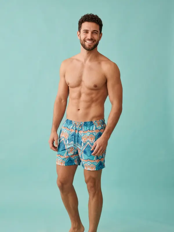 Symbolbild zu Gynäkomastie-OP, Penisvergrößerung und Lipo 360: lächelnder Mann in gemusterten Badeshorts